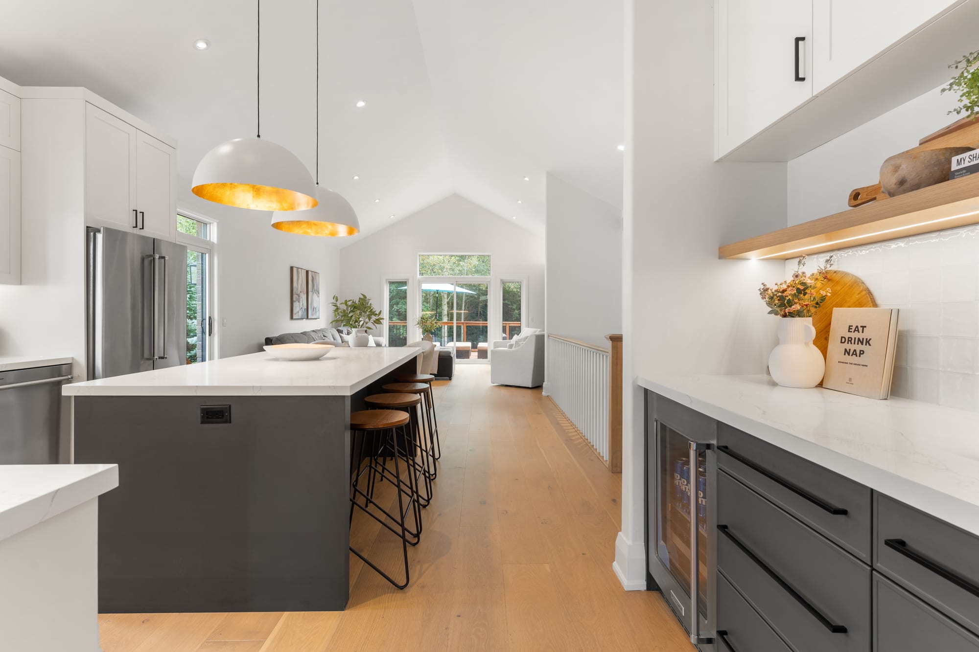 Chef's kitchen at 110 Mary Street, Collingwood, with a waterfall quartz island, gold-lined dome pendants and a beverage centre